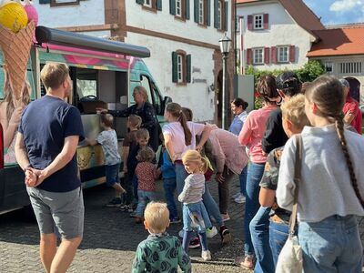 Kinder und Erwachsene stehen an einem Eiswagen im Freien Schlange