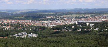 Bild mit einem Stadtpanorama von oben fotografiert. Stadt umgeben von vielen Wäldern