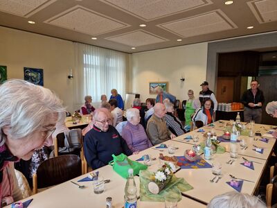 Bild mit gedeckten Tisch an dem Senioren und Seniorinnen sitzen