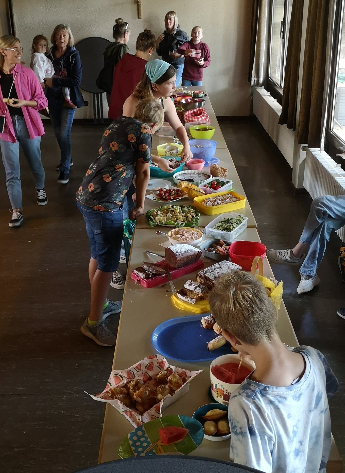 Tische mit vielen Speisen, Kinder und Erwachsene wählen Speisen aus
