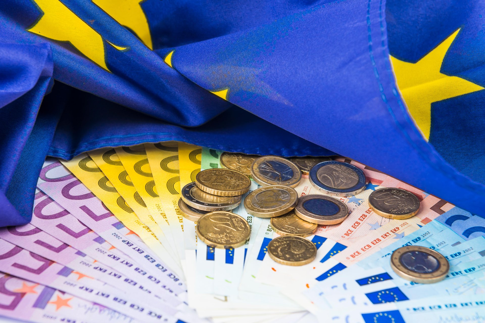 Diveres Eurogelscheine und Euromünzen unter eine EU-Flagee