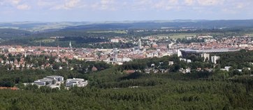 Bild mit einem Stadtpanorama von oben fotografiert. Stadt umgeben von vielen Wäldern